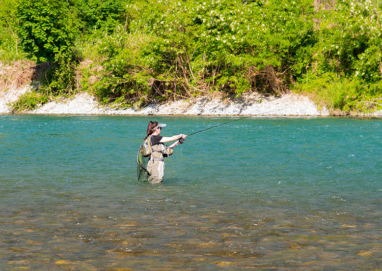 Femme en waders pêchant en rivière 